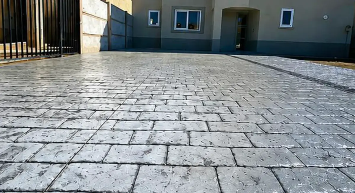 Patio delantero con hormigón estampado tipo adoquín en tono gris