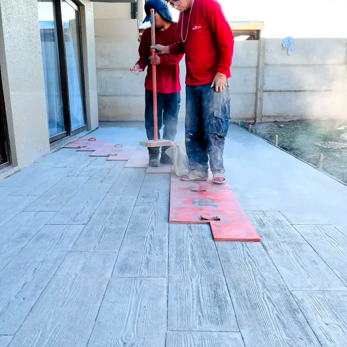 Dos integrantes del equipo de Rayen estampando un piso de hormigón con moldes